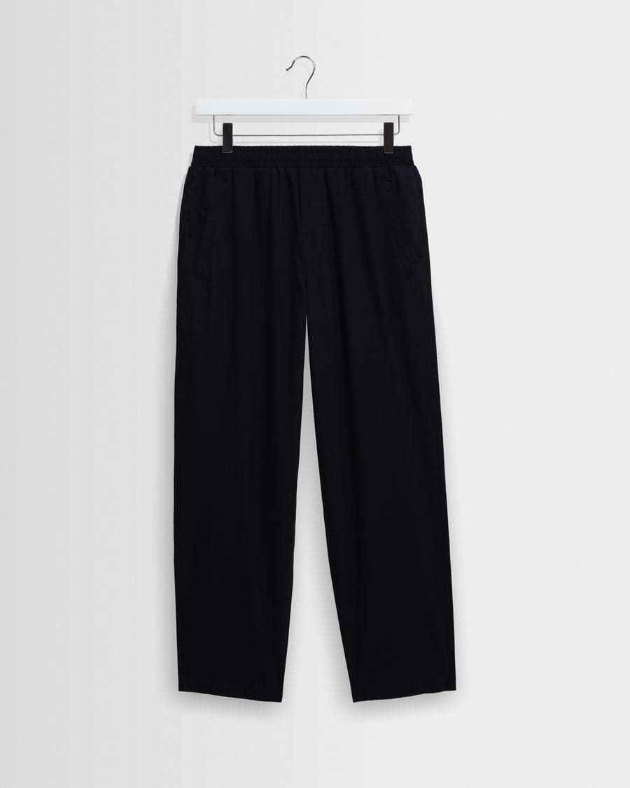 A pair of navy cotton-poplin loose-fit trousers — an anchor piece every capsule starts with