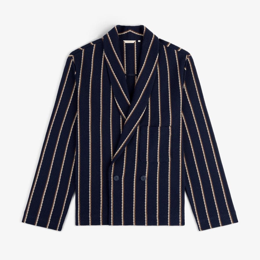 A navy striped shawl-collar jacket — the kind of fewer-better tailoring a 30s capsule invests in